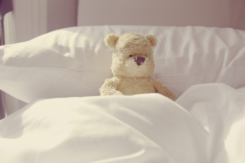 a child's teddy bear in the bed representing a child with sickness